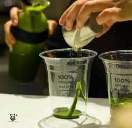 Barista pouring milk into a cup of organic matcha at a premium cafe counter